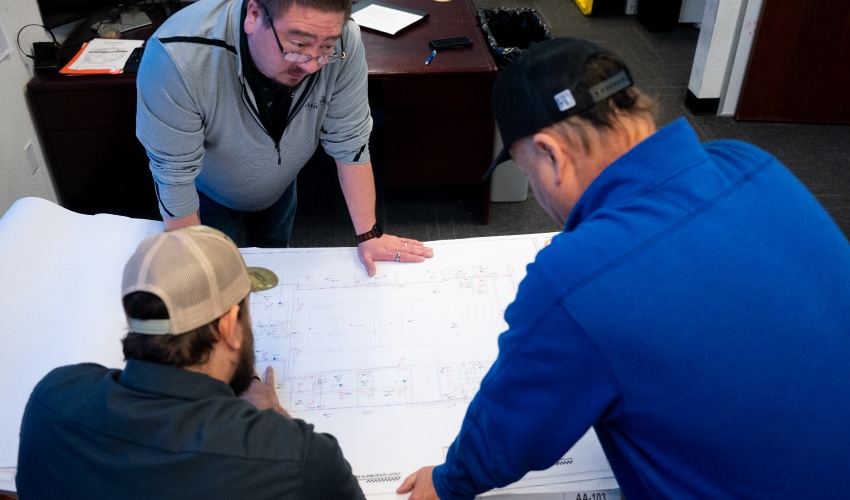 Professionals reviewing a large technical blueprint on a desk.